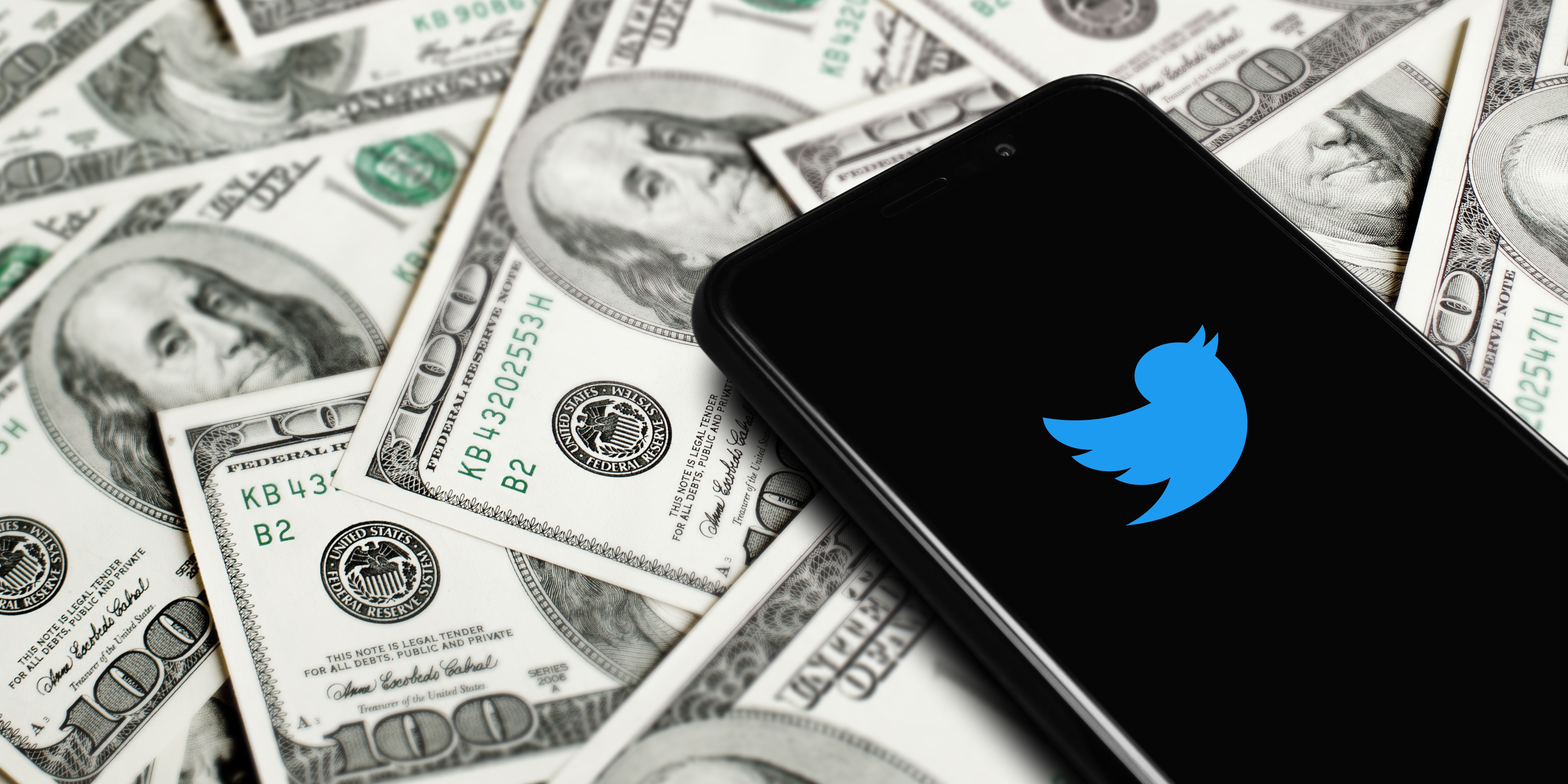 Twitterのロゴが映ったスマートフォンがドル紙幣の上に置かれている。